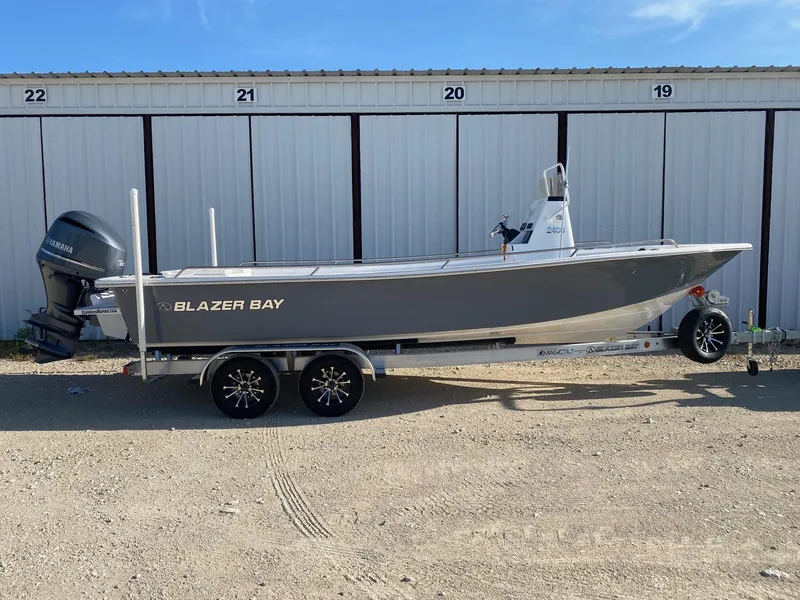 The Image of 2025 Blazer Bay 2400 Open Bay Striper boat on trailer, parked outdoors. - 0