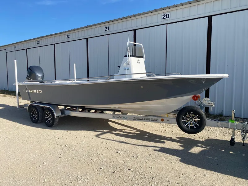 Slide: The Image of 2025 Blazer Bay 2400 Open Bay Striper boat on trailer, parked outdoors. - 1