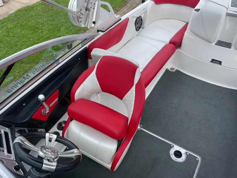 Slide: The Image of 2013 MasterCraft X-14V boat interior with red and white seating, steering wheel, and carpeted floor. - 7