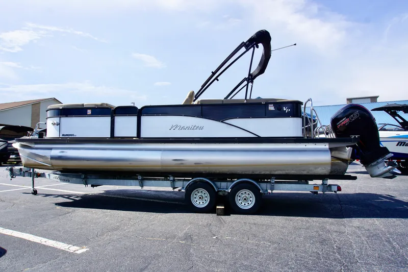 Slide: The Image of 2022 Manitou 23 Aurora LE RF pontoon boat on trailer, parked outdoors. - 0