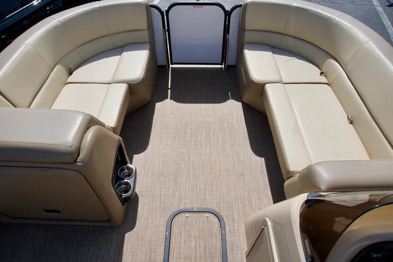 Slide: The Image of 2022 Manitou 23 Aurora LE RF boat interior with beige seating and carpeted floor. - 7