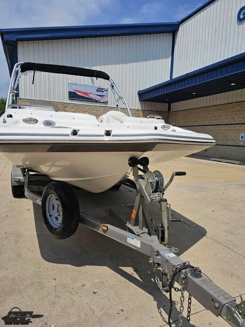 Slide: The Image of 2013 Hurricane SunDeck Sport 202 IO boat on trailer, parked outside a building. - 12