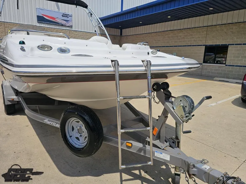Slide: The Image of 2013 Hurricane SunDeck Sport 202 IO boat on trailer, parked outside a building. - 13