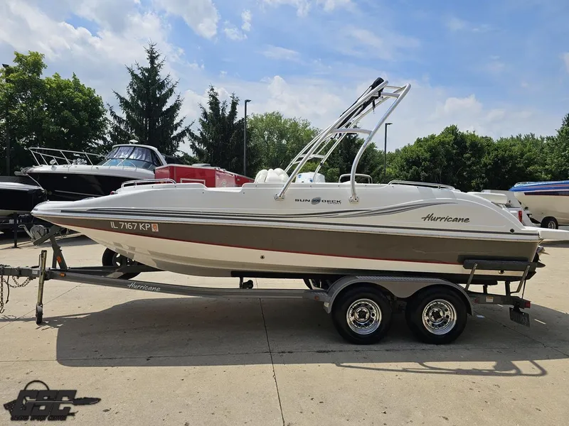 Slide: The Image of 2013 Hurricane SunDeck Sport 202 IO boat on trailer, parked outdoors under a blue sky. - 18
