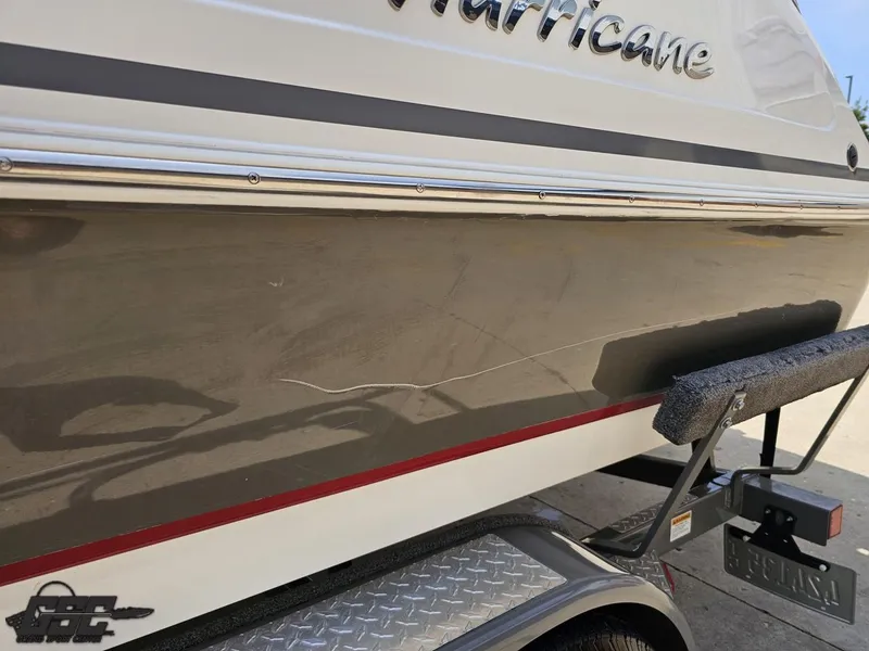 Slide: The Image of 2013 Hurricane SunDeck Sport 202 IO boat with visible hull scratch on trailer. - 23