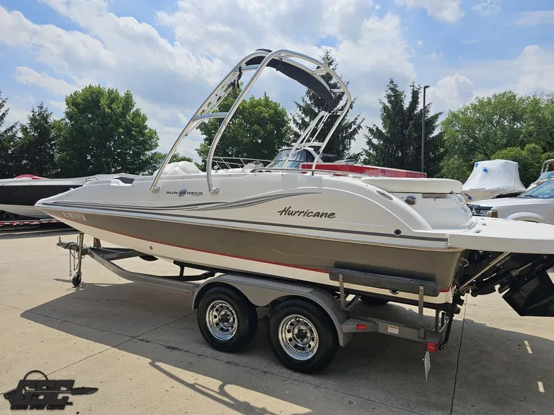 Slide: The Image of 2013 Hurricane SunDeck Sport 202 IO boat on trailer, parked outdoors under a cloudy sky. - 26