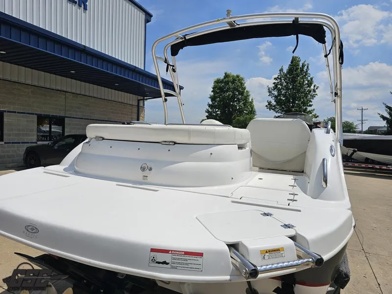 Slide: The Image of 2013 Hurricane SunDeck Sport 202 IO boat, white exterior, parked outdoors near a building. - 31