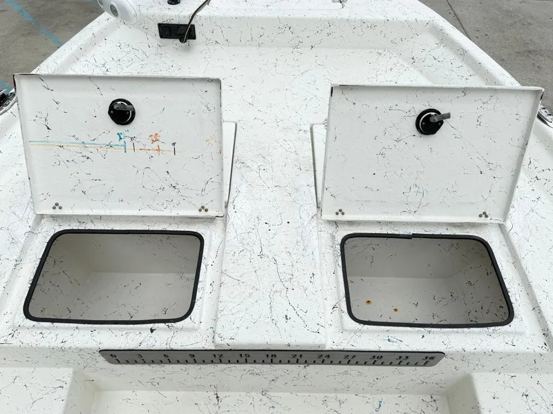 Slide: The Image of 2015 Blazer Bay 2400 boat storage compartments with open lids and measuring ruler. - 14