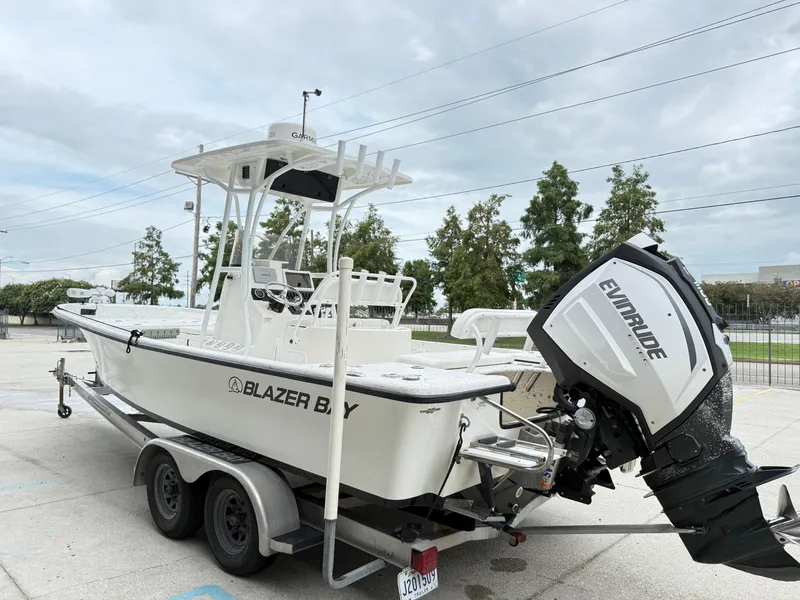 Slide: The Image of 2015 Blazer Bay 2400 boat with Evinrude engine on a trailer, parked outdoors. - 4