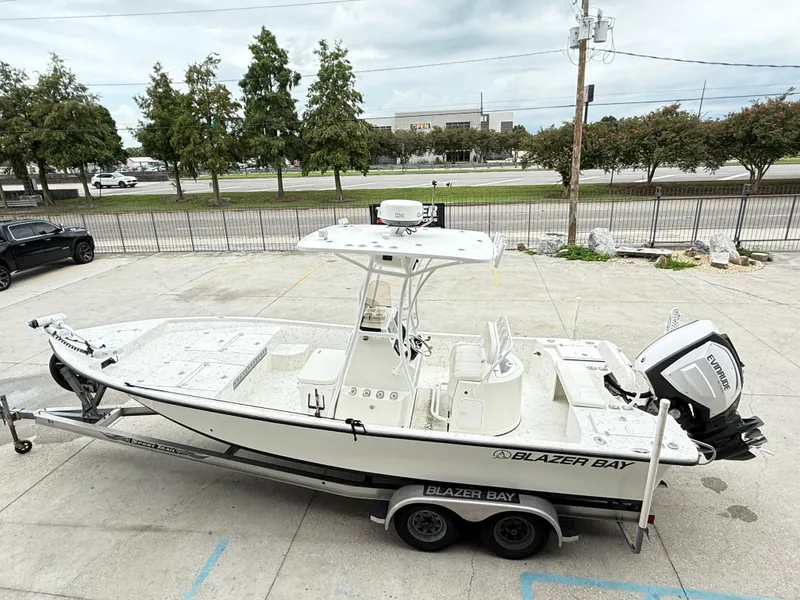 Slide: The Image of 2015 Blazer Bay 2400 boat on trailer, parked outdoors, featuring Evinrude engine. - 8