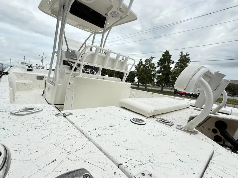 Slide: The Image of 2015 Blazer Bay 2400 boat interior with white seating and console, under cloudy sky. - 9