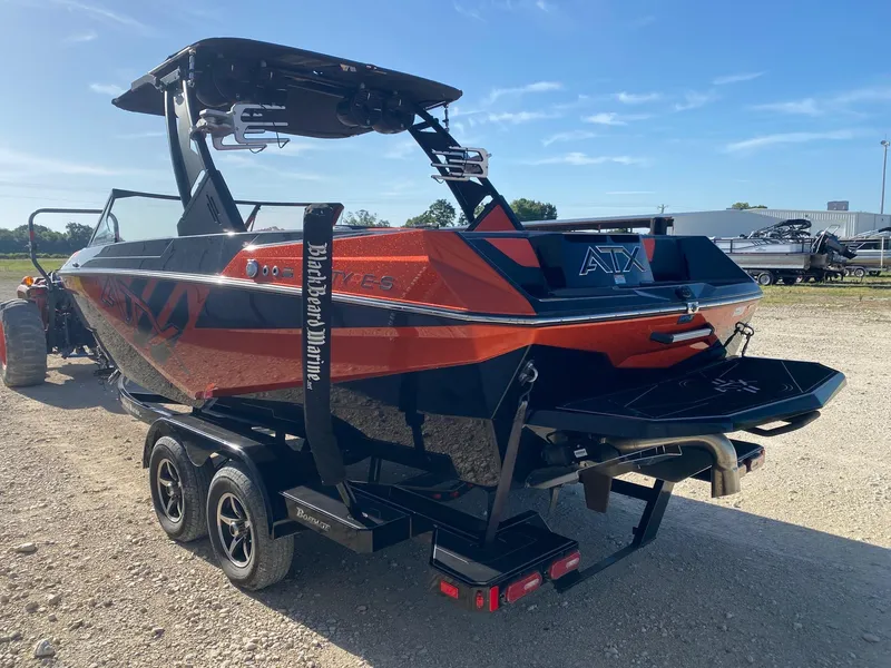 Slide: The Image of 2021 ATX Surf Boats 22 Type-S on trailer, orange and black design, parked outdoors. - 3