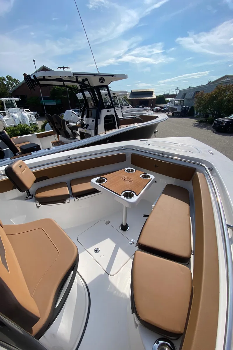 Slide: The Image of 2025 Sea Pro 222 Center Console boat with tan seating and table, docked outdoors. - 11
