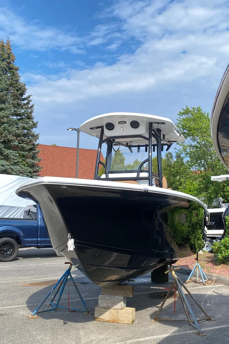 Slide: The Image of 2025 Sea Pro 222 Center Console boat on stands, outdoors under a partly cloudy sky. - 2