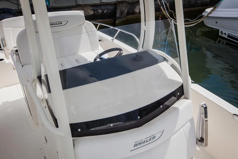 Slide: The Image of 2021 Boston Whaler 270 Dauntless boat console with steering wheel, docked by the water. - 17