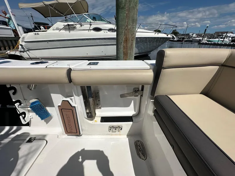 Slide: The Image of 2021 Tidewater 252 LXF boat interior with seating and footrest, docked at marina. - 14