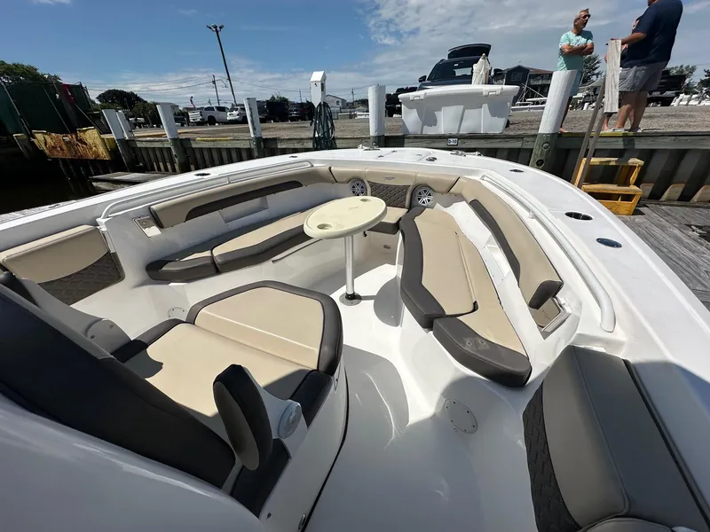 Slide: The Image of 2021 Tidewater 252 LXF boat interior with beige seating and table at dock. - 2