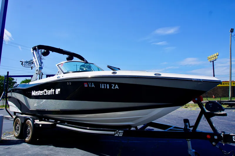 Slide: The Image of 2019 MasterCraft XT23 boat on trailer under clear blue sky. - 1