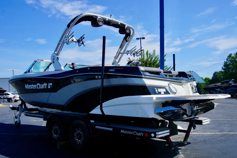 Slide: The Image of 2019 MasterCraft XT23 boat on trailer under clear blue sky. - 2