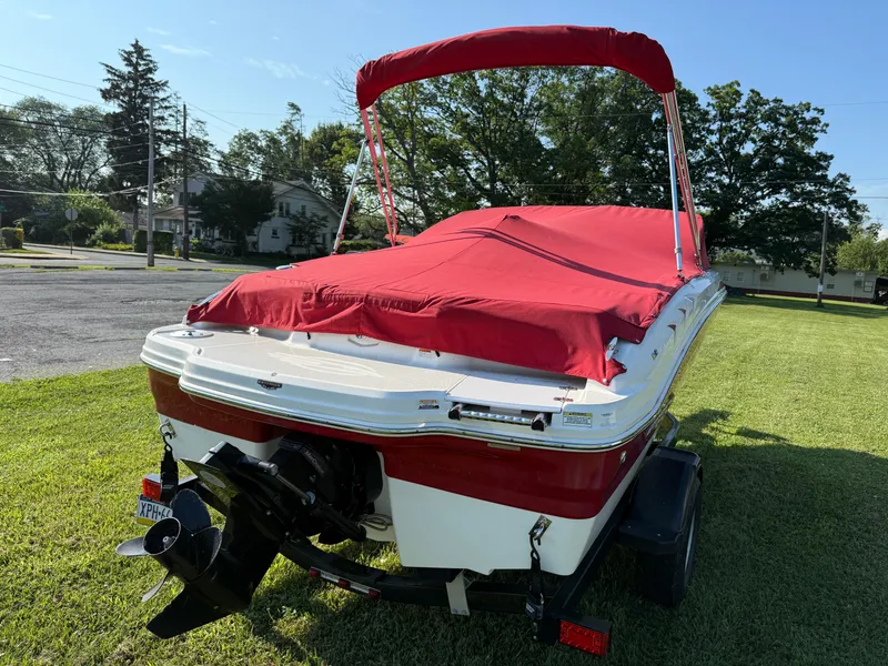 Slide: The Image of 2015 Chaparral 18 H2O Sport boat with red cover on grassy area. - 3