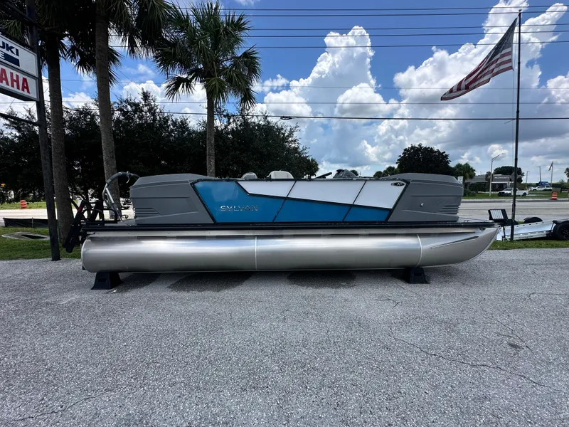 Slide: The Image of 2026 Sylvan A22 LZ Sport pontoon boat displayed outdoors with American flag and palm trees. - 5