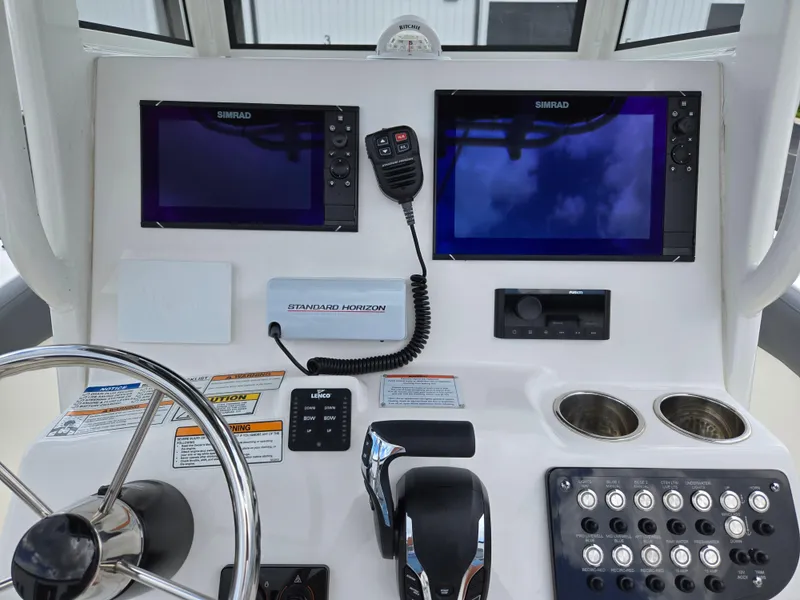 Slide: The Image of 2023 NauticStar 242L Offshore boat dashboard with dual Simrad displays and controls. - 15