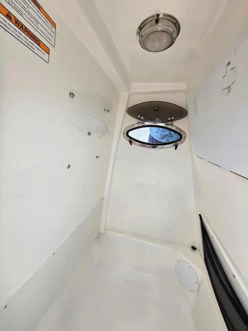 Slide: The Image of 2023 NauticStar 242L Offshore cabin interior with porthole and lighting. - 19