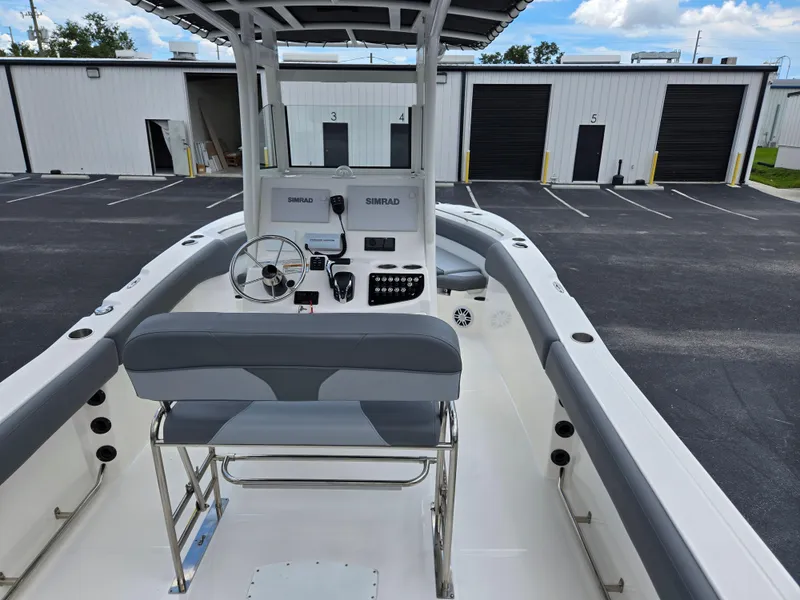 Slide: The Image of 2023 NauticStar 242L Offshore boat interior with steering console and seating in a parking lot. - 5