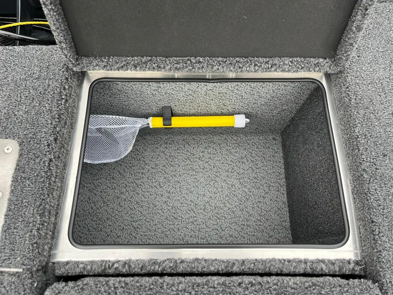 Slide: The Image of Storage compartment in 2026 Lund 2075 Pro-V Bass XS boat with a yellow-handled net. - 24