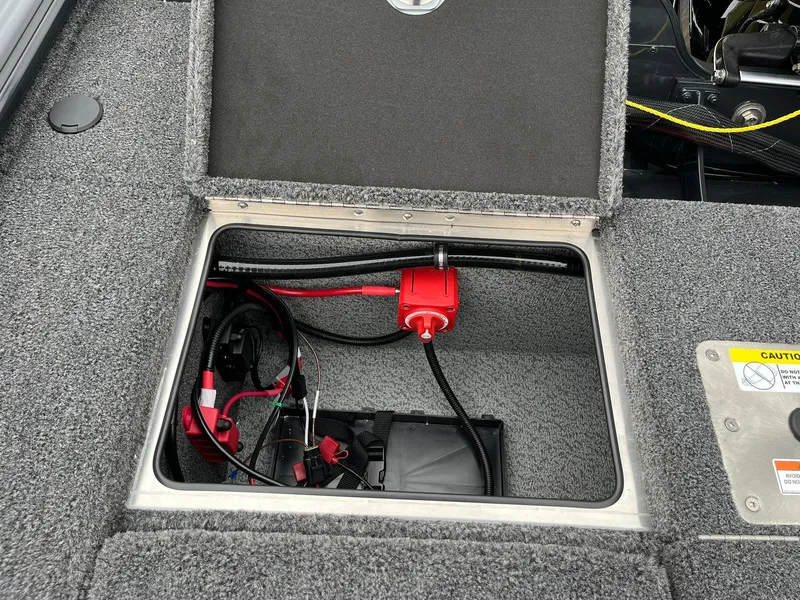 Slide: The Image of 2026 Lund 2075 Pro-V Bass XS boat battery compartment with wiring and safety features. - 25