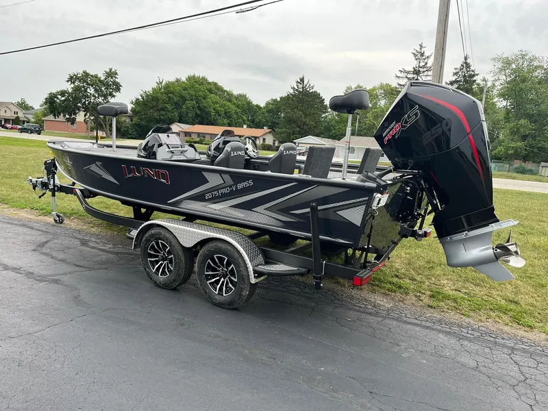 Slide: The Image of 2026 Lund 2075 Pro-V Bass XS boat on trailer, parked outdoors. - 4