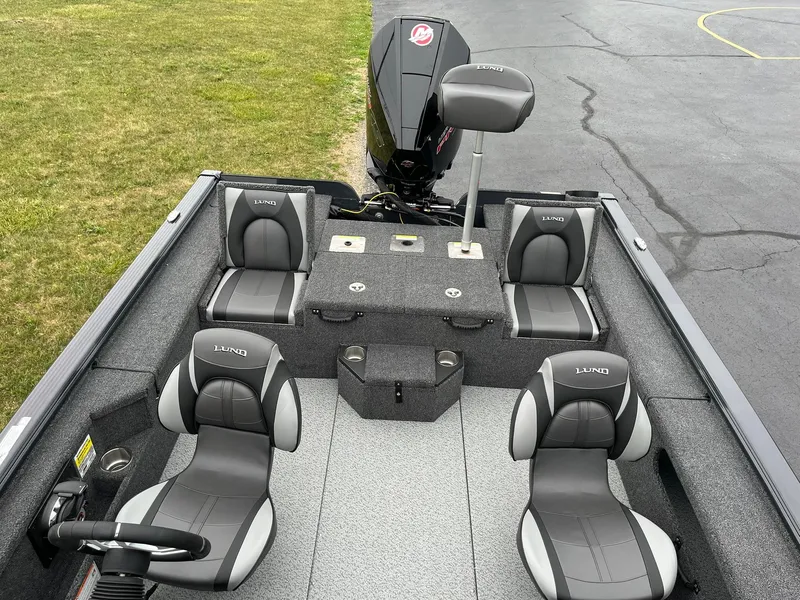 Slide: The Image of 2026 Lund 2075 Pro-V Bass XS boat interior with seating and motor, parked on pavement. - 7