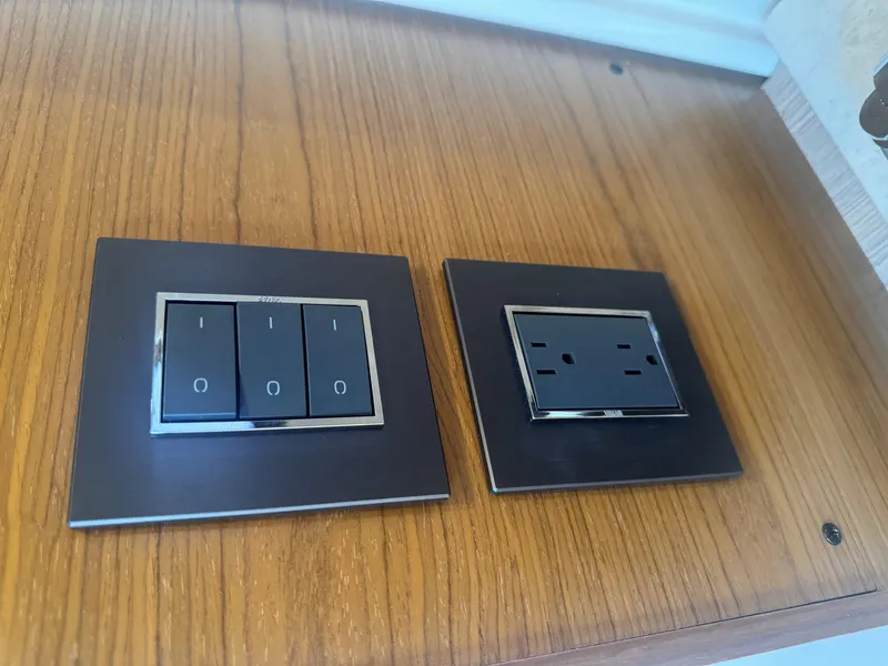 Slide: The Image of Modern light switches and outlet on Tiara Yachts 34 LS, 2023 model, wooden panel. - 11