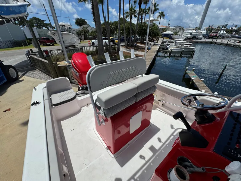 Slide: The Image of 2023 Clearwater 2200 boat interior with red console and seating at marina. - 12