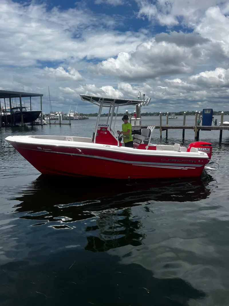 Slide: The Image of Red 2023 Clearwater 2200 boat docked on a sunny day with cloudy sky. - 3