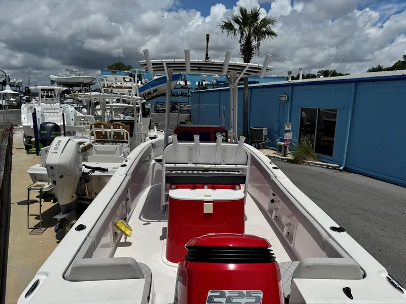 Slide: The Image of 2023 Clearwater 2200 boat with red motor, docked near blue building under cloudy sky. - 9