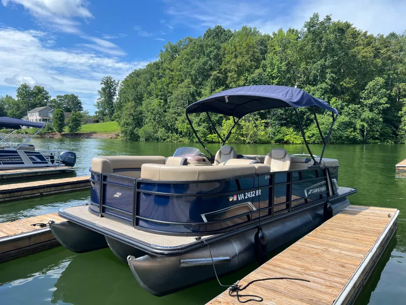 The Image of 2025 Starcraft EXS 3 pontoon boat docked on a serene lake with lush greenery. - 0