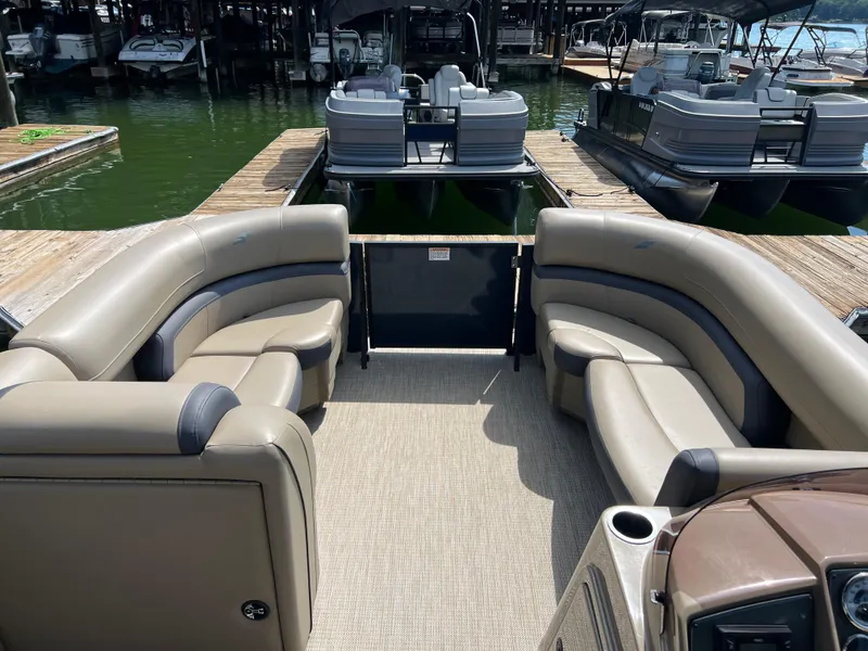 Slide: The Image of 2025 Starcraft EXS 3 pontoon boat interior with beige seating at a marina. - 5