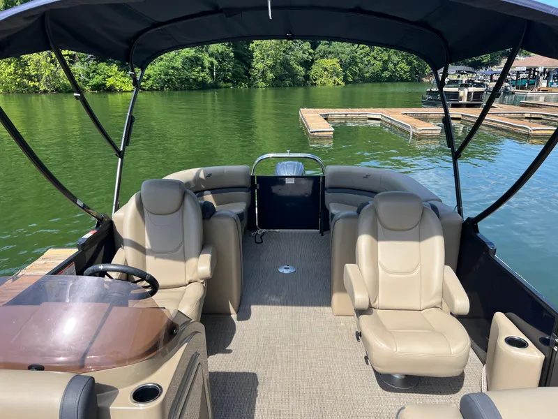 Slide: The Image of 2025 Starcraft EXS 3 pontoon boat interior with beige seating, docked on a serene lake. - 8