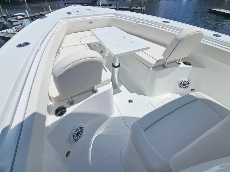 Slide: The Image of 2026 Sea Hunt Ultra 275 SE boat interior with seating and table, docked by the water. - 28