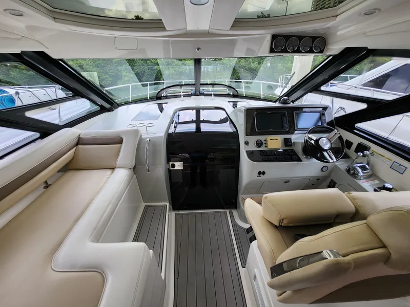 Slide: The Image of 2014 Sea Ray 470 Sundancer helm with luxurious seating and modern navigation equipment. - 14