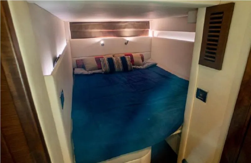 Slide: The Image of Cozy cabin interior of 2014 Sea Ray 470 Sundancer with blue bedding and ambient lighting. - 47