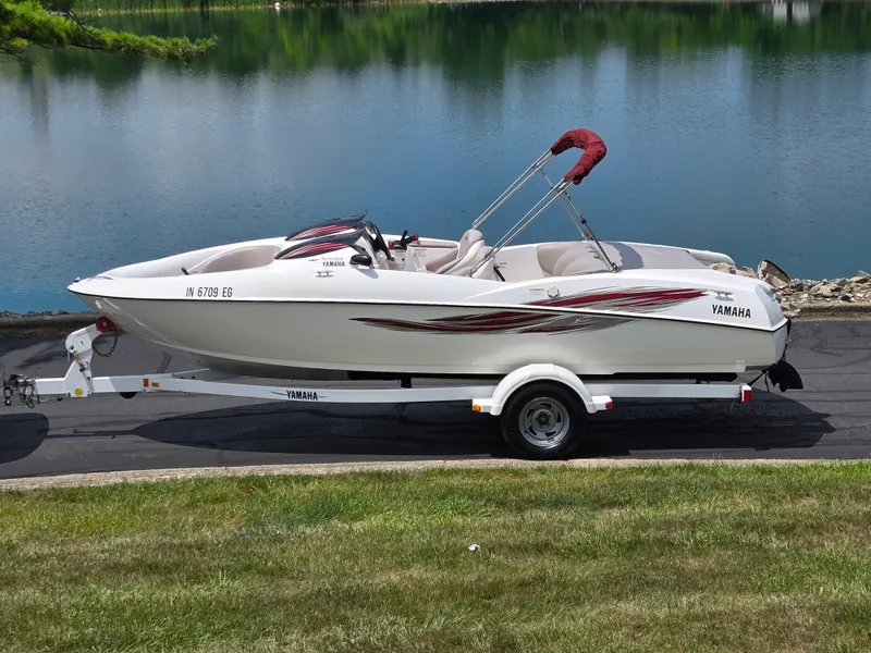 Slide: The Image of 2001 Yamaha LS 2000 boat on trailer by a serene lake. - 0
