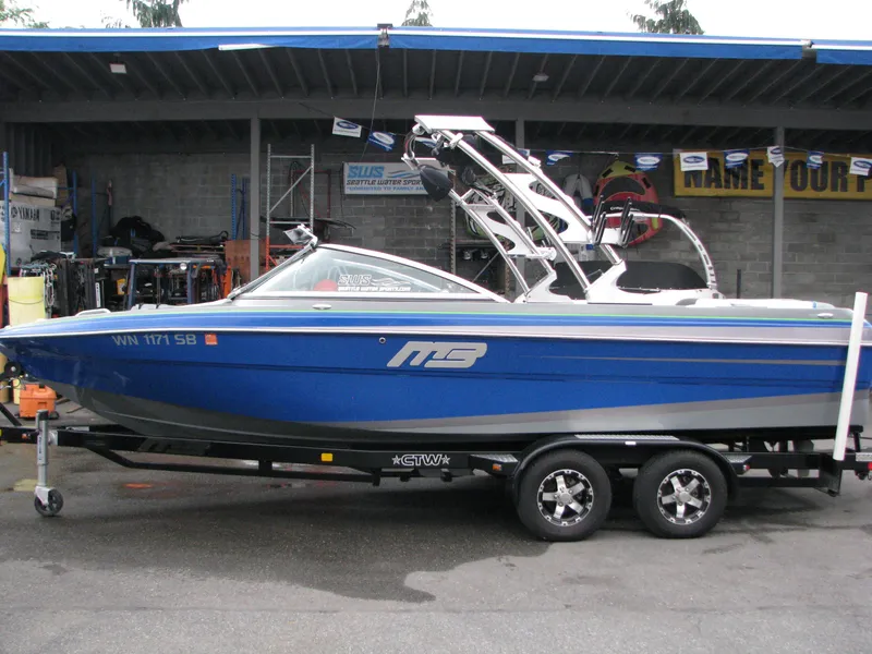The Image of Blue 2014 MB B-52 23 Widebody boat on trailer, parked in a garage. - 0