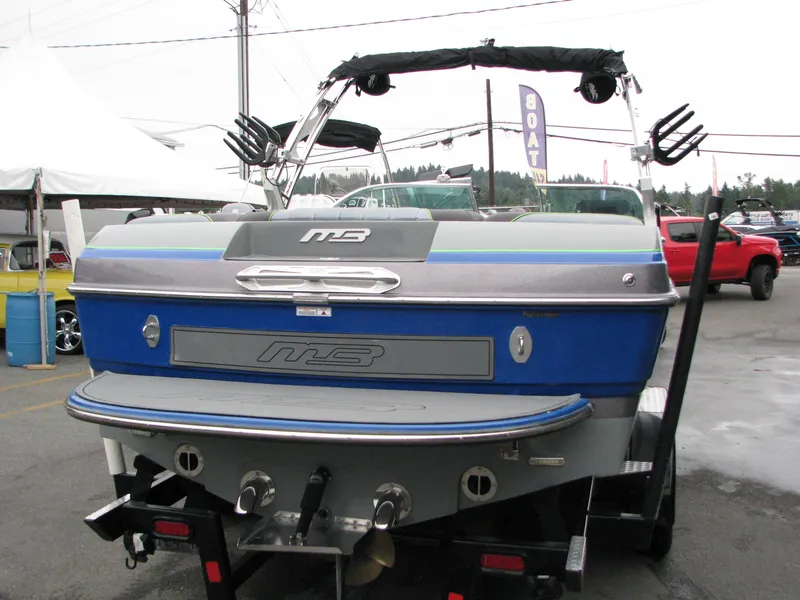Slide: The Image of 2014 MB B-52 23 Widebody boat, blue and silver, displayed outdoors on a trailer. - 3