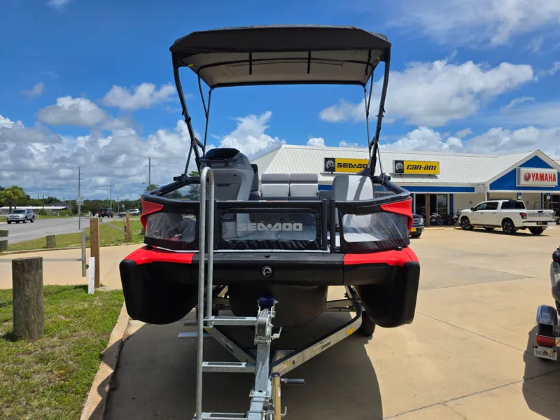 Slide: The Image of 2025 Sea-Doo Switch Compact Sport boat on trailer, parked outside dealership under blue sky. - 3