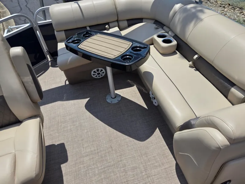Slide: The Image of 2022 Sun Tracker Party Barge 20 DLX interior with beige seating and central table. - 12