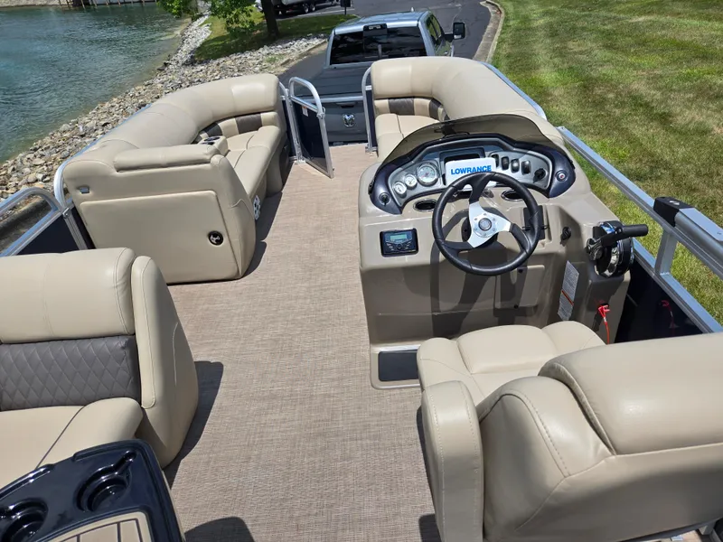 Slide: The Image of 2022 Sun Tracker Party Barge 20 DLX interior with beige seating and steering console. - 16