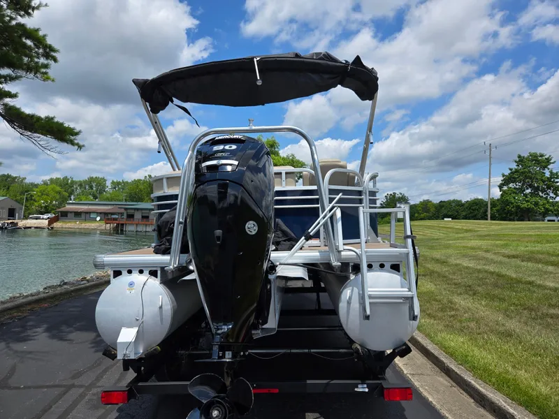 Slide: The Image of 2022 Sun Tracker Party Barge 20 DLX pontoon boat with outboard motor, docked by a lake. - 2