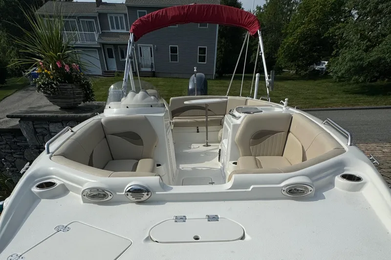 Slide: The Image of 2014 NauticStar 203SC Sport Deck boat with beige seating and red canopy, parked outdoors. - 12